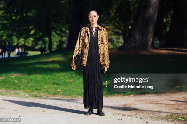 Model Jing Wen wears a leopard fur jacket, black purse, and long pleated black dress with black shoes during Milan Fashion Week Spring/Summer 2018 on...