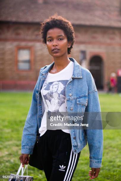 Model Isilda Moreira exits the MSMG shirt in a denim jacket, white Guess advertisement tshirt, and black Adidas track pants during Milan Fashion Week...