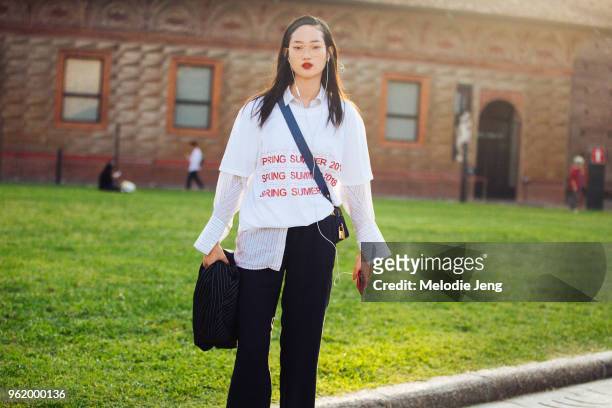 Korean model Hyun Ji Shin wears thin-framed glasses, listens to music on her earphones, and wears a Spring/Summer 2018 MSGM tshirt over a striped...
