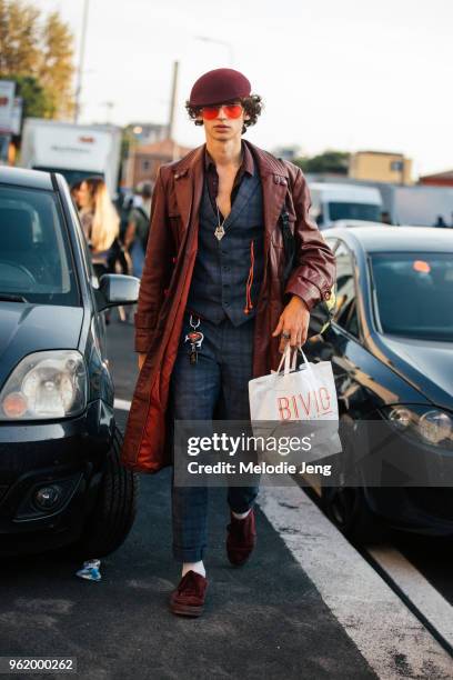 Model Quintin Van Konkelenberg wears a red hat, sunglasses, long black leather jacket, matching blue plaid vest and pants, red sneakers during Milan...