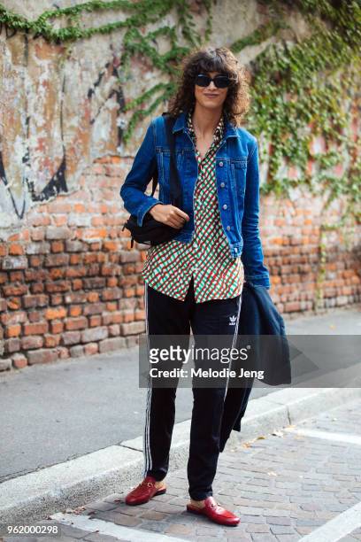 Model Mica Arganaraz wears a denim jacket, red and green gingham top, black Adidas trackpants, red Gucci loafers, black sunglasses, and a Prada fanny...
