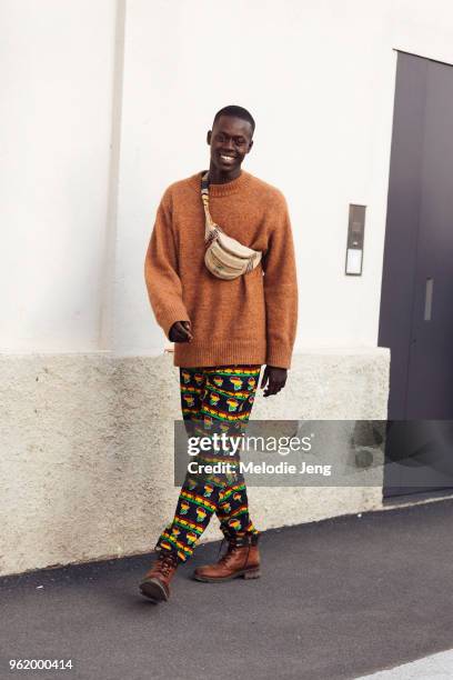 Model Alpha Dia wears a hemp fanny pack, orange sweater, Senegal color African print pants, and brown boots during Milan Fashion Week Spring/Summer...