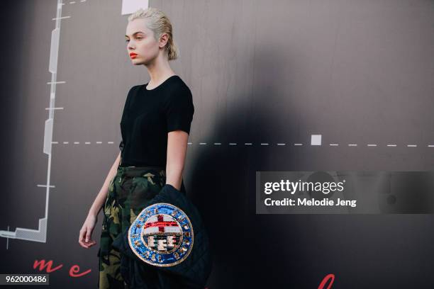 Model Emma Boyd wears a black top, camouflage pants, and carries a sequin jacket during Milan Fashion Week Spring/Summer 2018 on September 24, 2017...