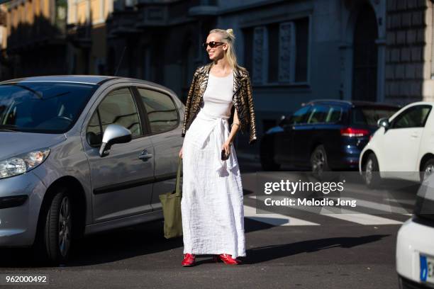 Model Lili Sumner wears sunglasses, a leopard print jacket off her shoulders, a white tank top, and white summer cotton skirt during Milan Fashion...