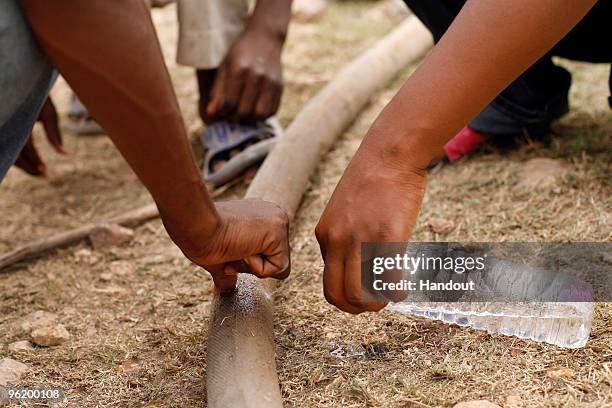 In this handout image provided by the United Nations Stabilization Mission in Haiti , people collect water from a leaking water hose as the Agency...