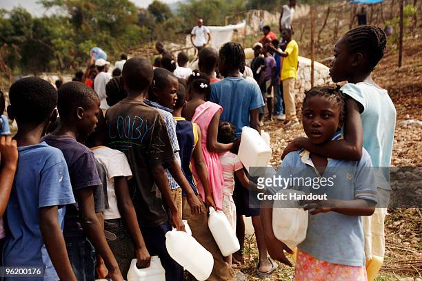 In this handout image provided by the United Nations Stabilization Mission in Haiti , people wait to collect water as the Agency for Technical...