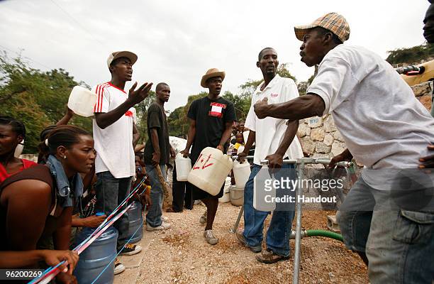 In this handout image provided by the United Nations Stabilization Mission in Haiti , a man fills containers of water as others look on in an...