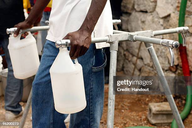 In this handout image provided by the United Nations Stabilization Mission in Haiti , a man fills containers of water in internally displaced persons...