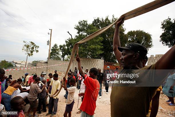 In this handout image provided by the United Nations Stabilization Mission in Haiti , people hold up a water hose as the Agency for Technical...