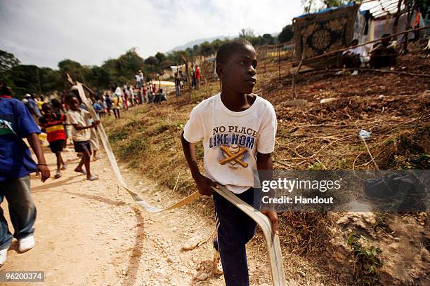 In this handout image provided by the United Nations Stabilization Mission in Haiti , a boy holds up a water hose as the Agency for Technical...