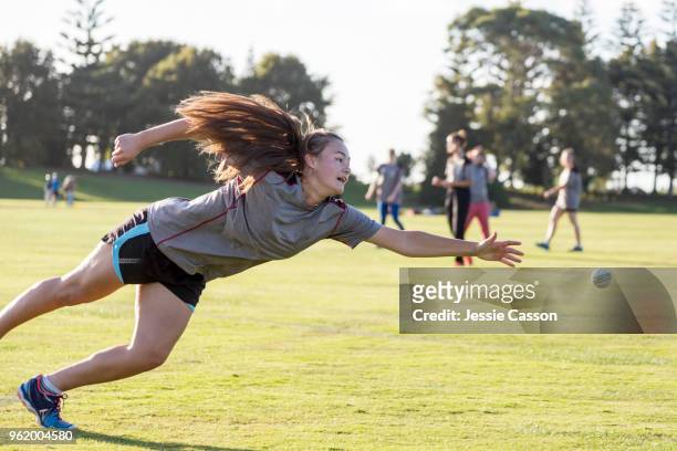 a female cricketer dives to catch the ball - new zealand cricket stock pictures, royalty-free photos & images
