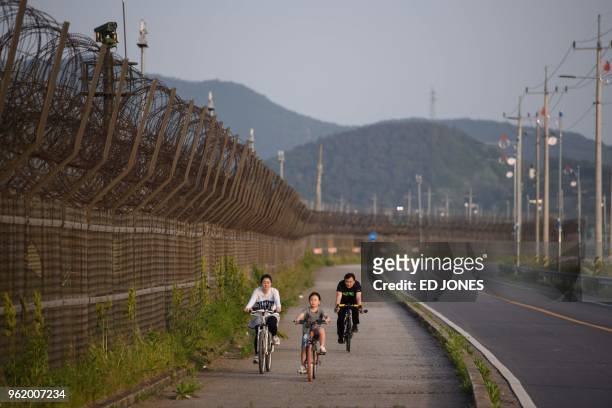 Family ride bicycles along a barbed wire fence of the Demilitarized Zone separating North and South Korea, on Ganghwa island on May 24, 2018. - North...