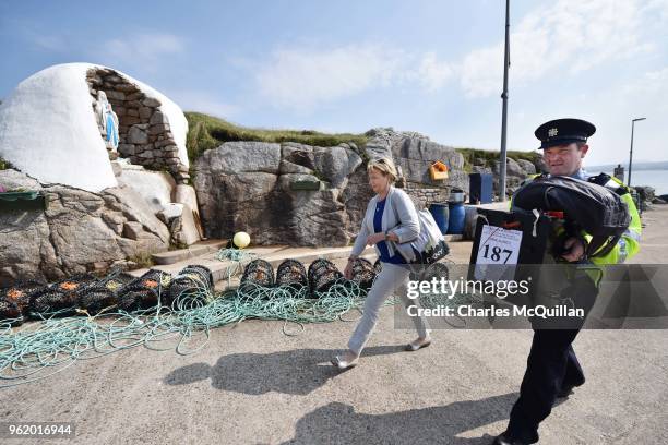 Garda officer Pat McElroy helps presiding officer Nancy Sharkey carry a ballot box as they walk past a Holy Shrine to the local polling station as...