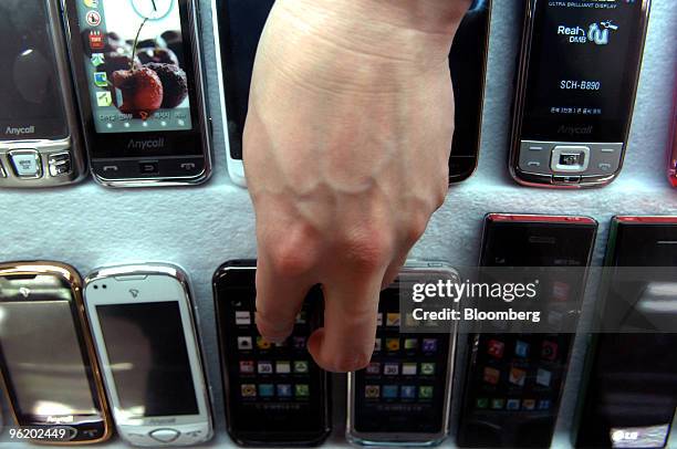 Sales clerk displays LG electronics Co.'s handsets at an electronics shop in Seoul, South Korea, on Wednesday, Jan. 27, 2010. LG Electronics Inc.,...