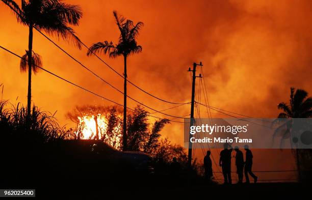 Lava erupts from a Kilauea volcano fissure as people gather on a residential street in Leilani Gardens, on Hawaii's Big Island, on May 23, 2018 in...