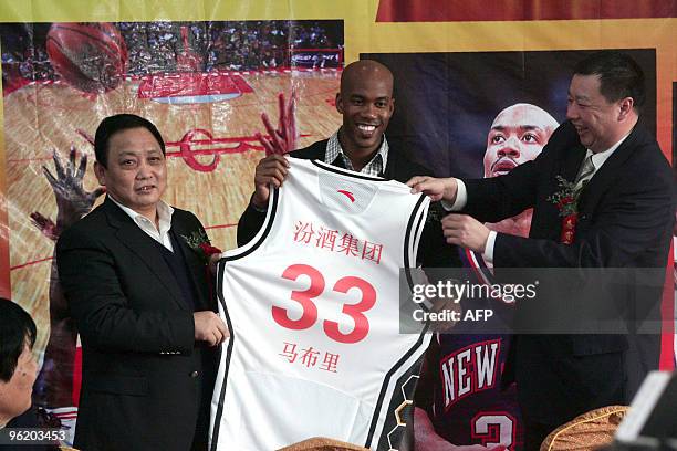 Former NBA All Star Stephon Marbury poses with his new jersey together with the officials of Shanxi Zhongyu team, after signing his contract in...