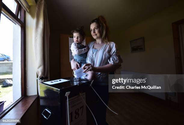 Colleen Ui Fhroruisce casts her vote as she holds her daughter Saoirse as voting takes place a day earlier than the main land on May 24, 2018 in Gola...