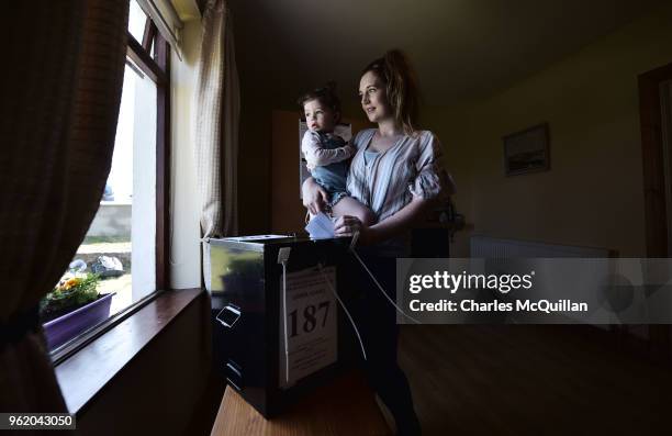 Colleen Ui Fhroruisce casts her vote as she holds her daughter Saoirse as voting takes place a day earlier than the main land on May 24, 2018 in Gola...