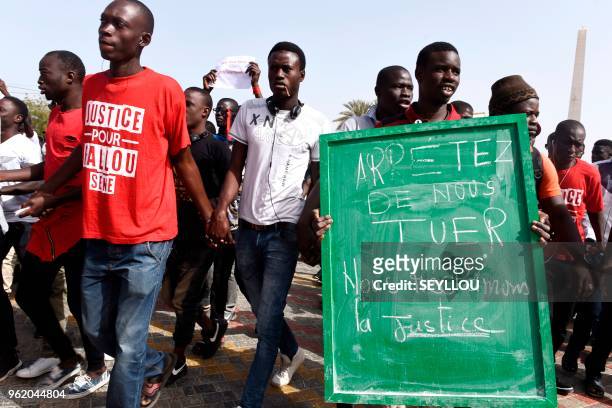 Man holds a placard, reading "Stop killing us, We want justice", while students and relatives demonstrate on May 24, 2018 in Dakar, to demand justice...
