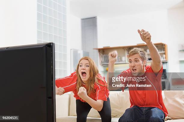 world cup couple shouting at television - couple watching tv photos et images de collection