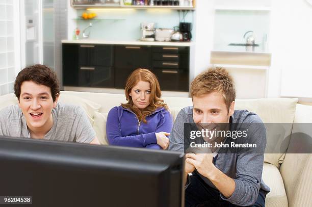 bored girl ignores tv while guys are oblivious - oblivious stock pictures, royalty-free photos & images