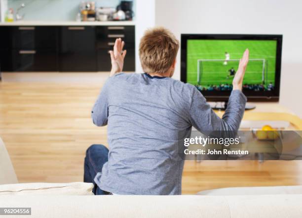 tense football fan waving arms at television match - competition round stock pictures, royalty-free photos & images