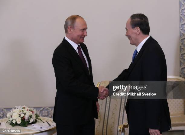 Russian President Vladimir Putin shakes hands with Chinese Vice President Wang Qishan during their bilateral meeting at Konstantin Palace on May 24,...