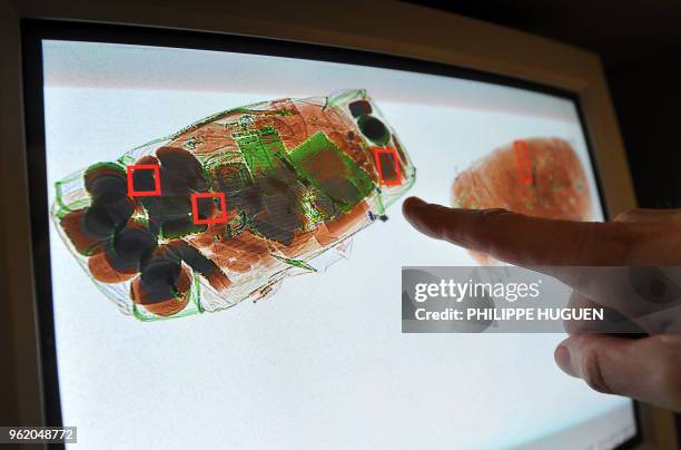 Lille's French customs officer points on a screen suspicious items scanned from the suitcase of a bus passenger on February 3, 2011 at the Rekkem...