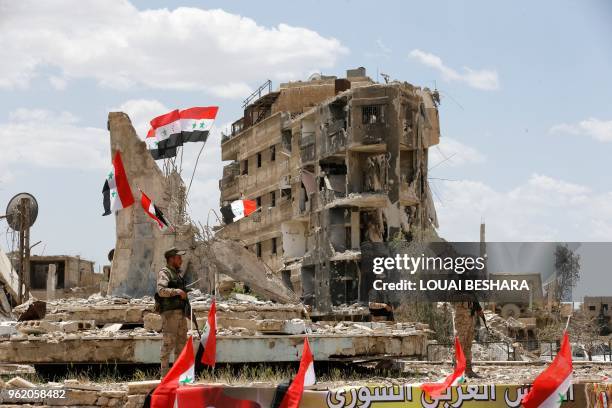 Regime forces attend a flag raising ceremony at the entrance of the Hajar al-Aswad neighbourhood on the southern outskirts of the capital Damascus on...