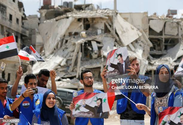 Members of the Revolutionary Youth Union, the youth organization of the Arab Socialist Baath Party in Syria, wave their national flag and portraits...