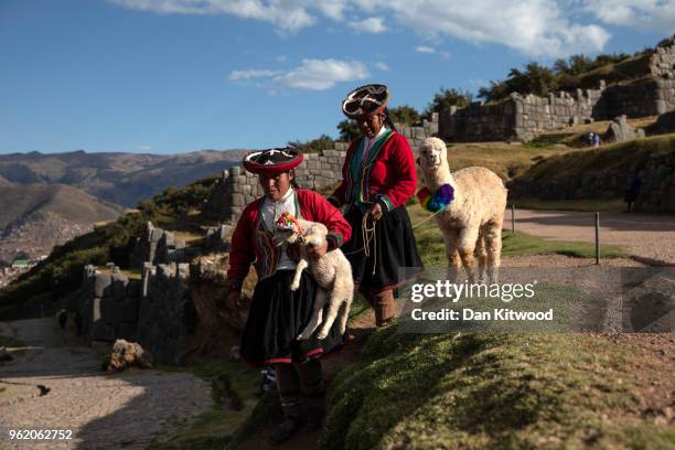 Quechua women walk through the Inca ruins of Sacsayhuaman looking to pose for photographs in exchange for money on May 23, 2018 in Cusco, Peru. At...