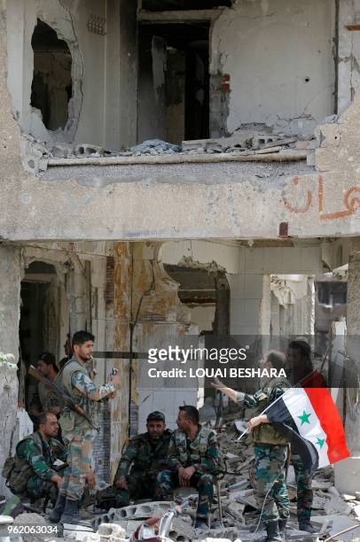 Pro-government forces rest during a flag raising ceremony at the entrance of the Hajar al-Aswad neighbourhood on the southern outskirts of the...