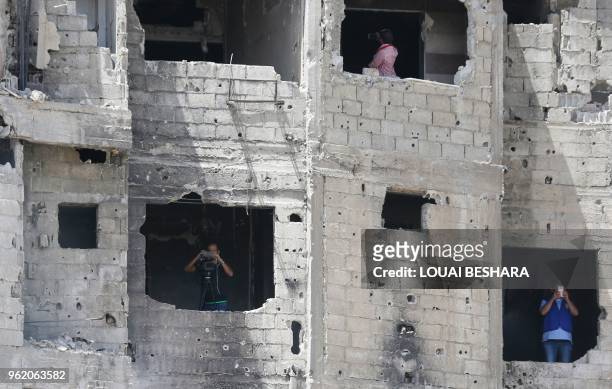 Syrians film and take photos from the windows of a destroyed building during a flag raising ceremony at the entrance of the Hajar al-Aswad...