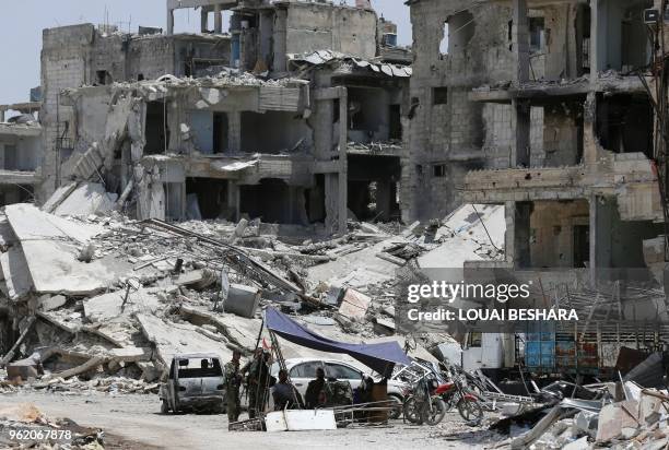 Syrian pro-government forces rest in the shade following a flag raising ceremony at the entrance of the Hajar al-Aswad neighbourhood on the southern...