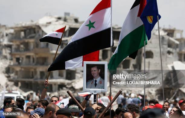 Civilian raises a portrait of the Syrian president during a flag raising ceremony at the entrance of Hajar al-Aswad on the southern outskirts of the...