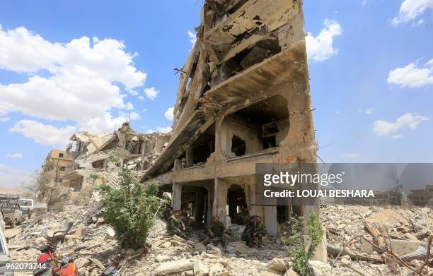 Syrian pro-regime forces sit in the shade of a damaged building on Thalateen Street in the Yarmuk Palestinian refugee camp on the southern outskirts...
