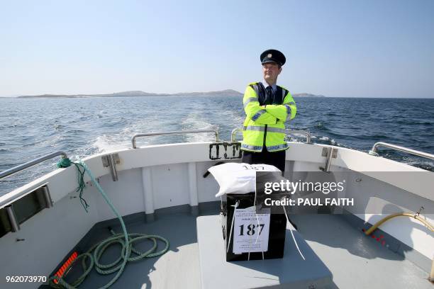 Garda officer Pat McElroy stands with the sealed ballot box as he travels back to the mainland from Gola Island, off the Donegal coast of western...