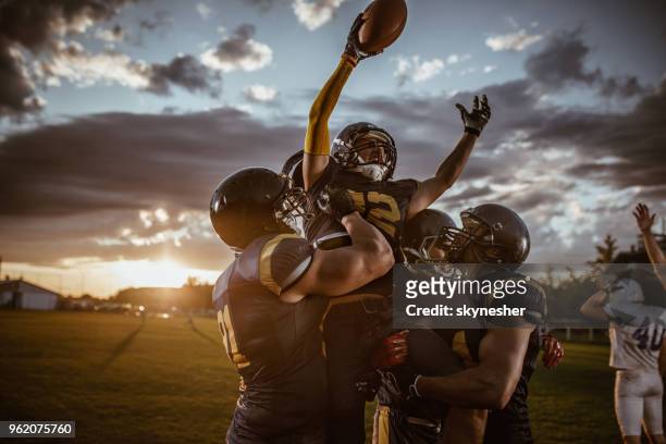 team of american football players celebrating victory at sunset. - american football player celebrating stock pictures, royalty-free photos & images