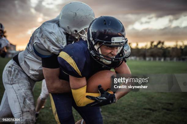determined american football player trying to pass defensive player on a match. - tackling stock pictures, royalty-free photos & images