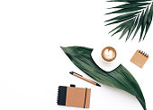 Creative flat lay background for blogger, keyboard, coffee cup and headphones with green leaves. Minimal workspace