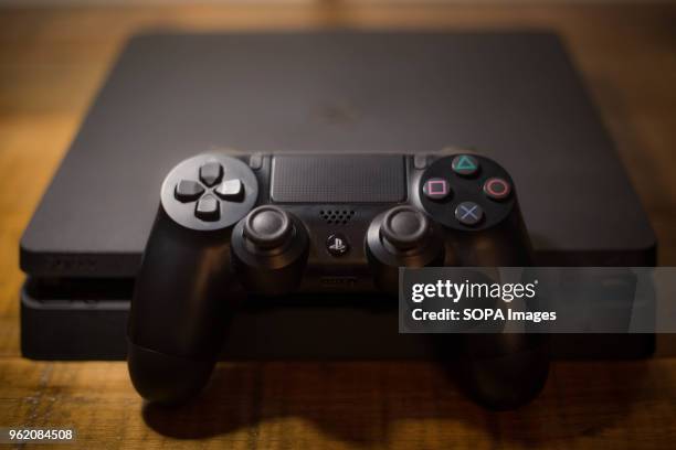 Sony PlayStation 4 video game console with a black wireless controller next to it. The PlayStation 4 or PS4 is knows as the eighth generation of home...