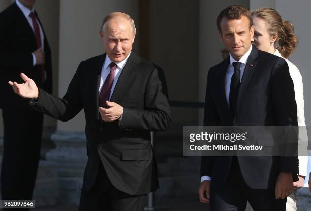 Russian President Vladimir Putin talks to French President Emmanuel Macron during their meeting at the Konstantin Palace in Saint Petersburg Russia,...