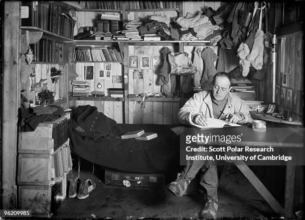Captain Robert Falcon Scott writes his journal in the Winterquarters Hut, in the Ross Dependency of Antarctica, during his Terra Nova Expedition to...