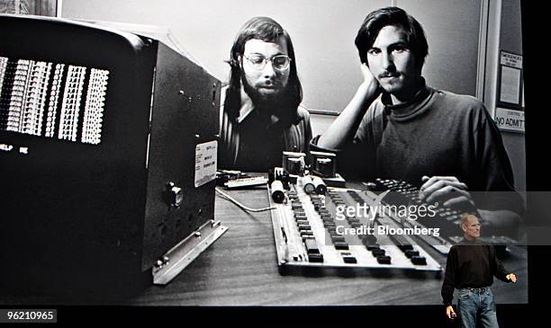 Steve Jobs, chief executive officer of Apple Inc., right, speaks in front of a file photograph of himself and Apple co-founder Steve Wozniak during...