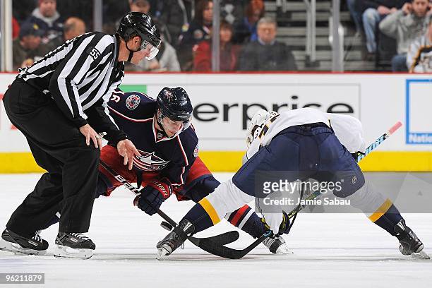 Forward Derick Brassard of the Columbus Blue Jackets takes a face off against the Nashville Predators as linesman Shane Heyer drops the puck on...