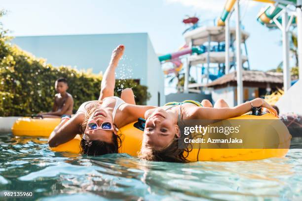 mujeres mirando a la cámara en floaties en la piscina - tobogán de agua fotografías e imágenes de stock