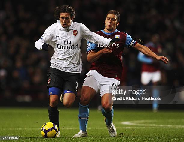 Tomas Rosicky of Arsenal is challenged from behind by Stiliyan Petrov of Aston Villa during the Barclays Premier League match between Aston Villa and...
