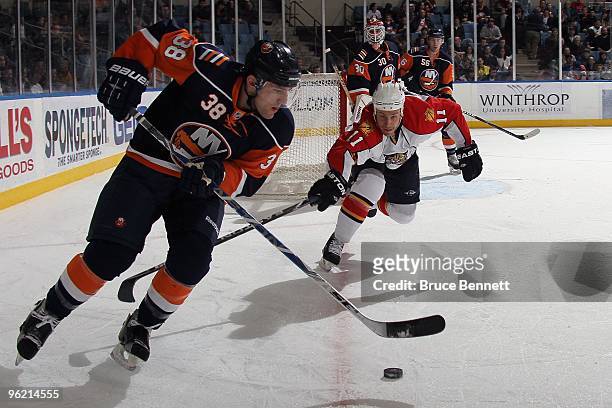 Jack Hillen of the New York Islanders skates with the puck against Gregory Campbell of the Florida Panthers at the Nassau Coliseum on January 21,...