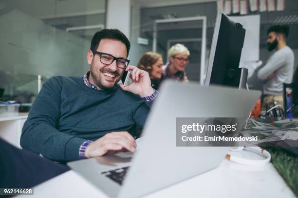 computer programmer using mobile phone while working on laptop - web programmer stock pictures, royalty-free photos & images