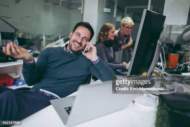 computer programmer using mobile phone while working on laptop - web programmer stock pictures, royalty-free photos & images